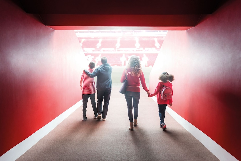 Couples walk through a tunnel at Liverpool Football Club stadium