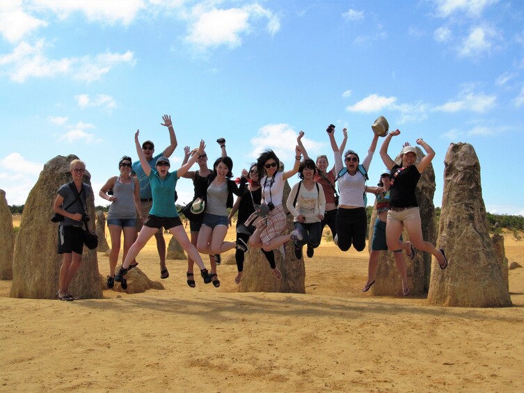 Group jumping in the air in the Pinnacles Desert in Perth