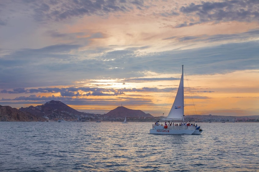 Landscape sunset views of a sailboat sailing along Cabo San Lucas Bay