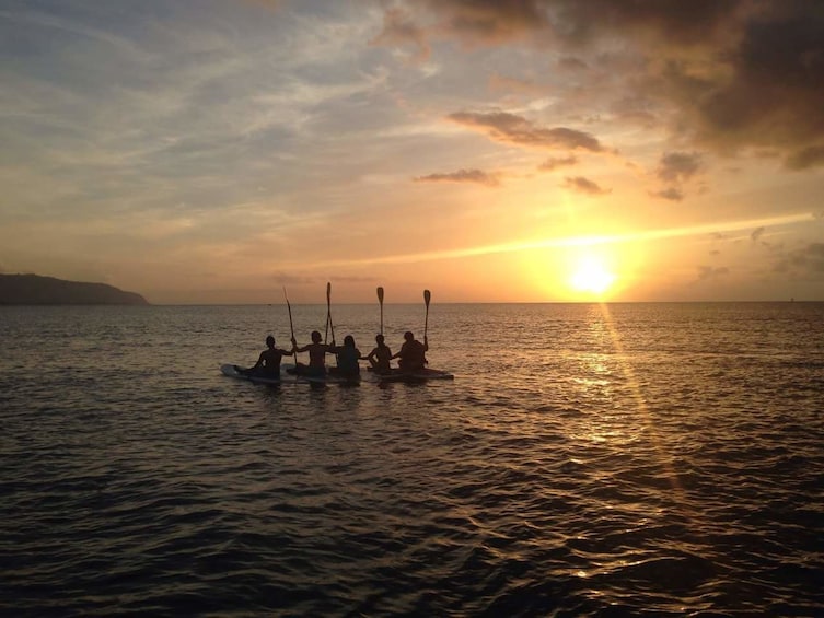Group enjoying the sunset while stand up paddle boarding in Haleiwa
