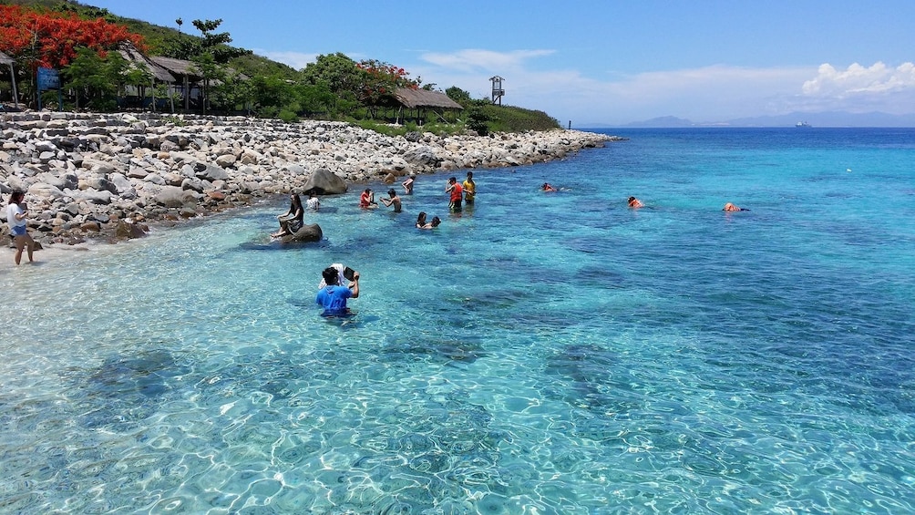 People swim in clear, shallow water near Hon Mun Island in Vietnam