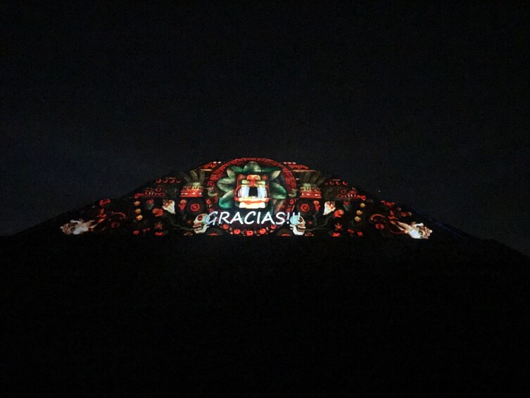 Projected design that says "Gracias" on pyramids of Teotihuacan