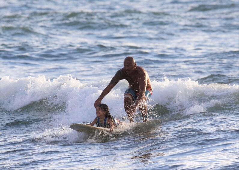 Man surfing with a child in Haleiwa