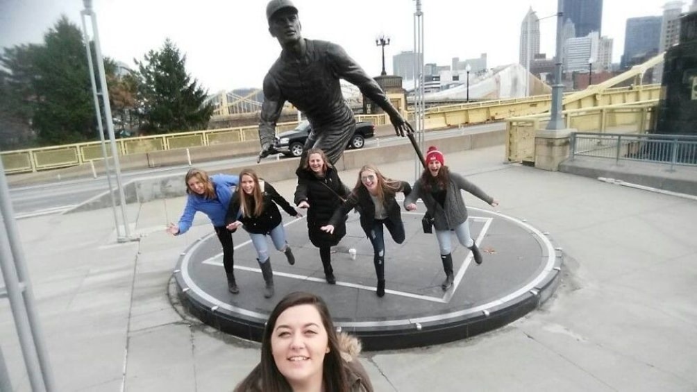 Show item 4 of 4. Group taking photo next to a statue