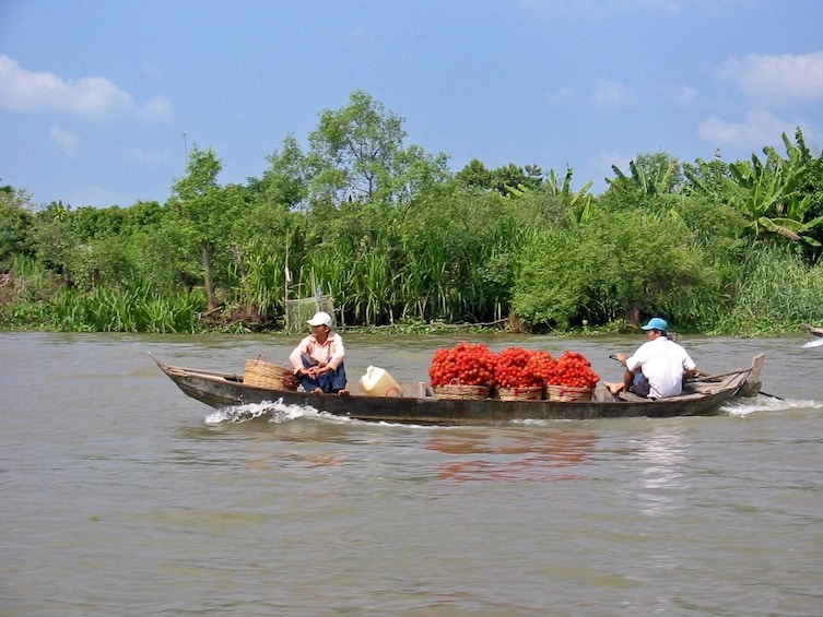 Locals transporting goods via a wooden boat on Tien River 