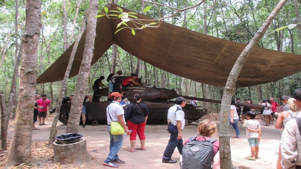 Tourists with an old tank at site of Cu Chi Tunnels in Vietnam