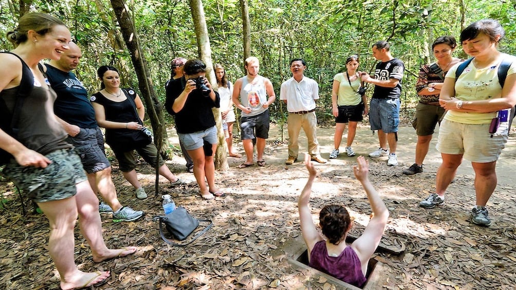 Crowd watches as woman lowers herself into secret opening of Cu Chi Tunnels
