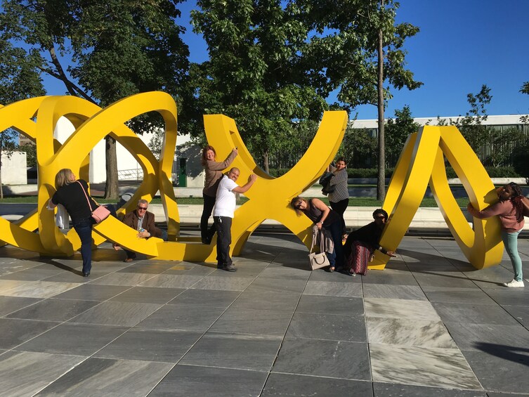 Show item 4 of 4. Tour group playing with a sculpture on the street