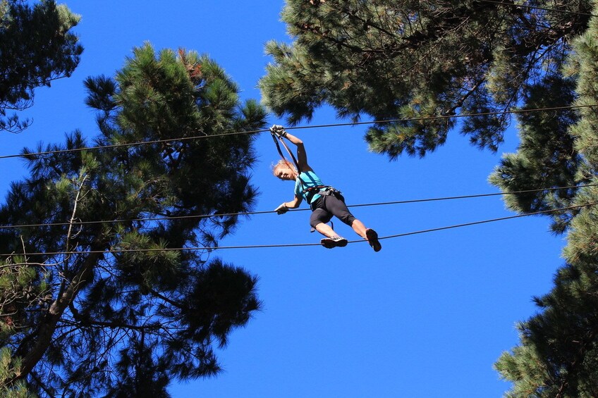 Woman walking a tightrope in between the trees in New Zealand