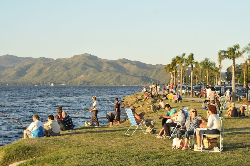 Gathering of people sit next to the water in Villa Carlos Paz