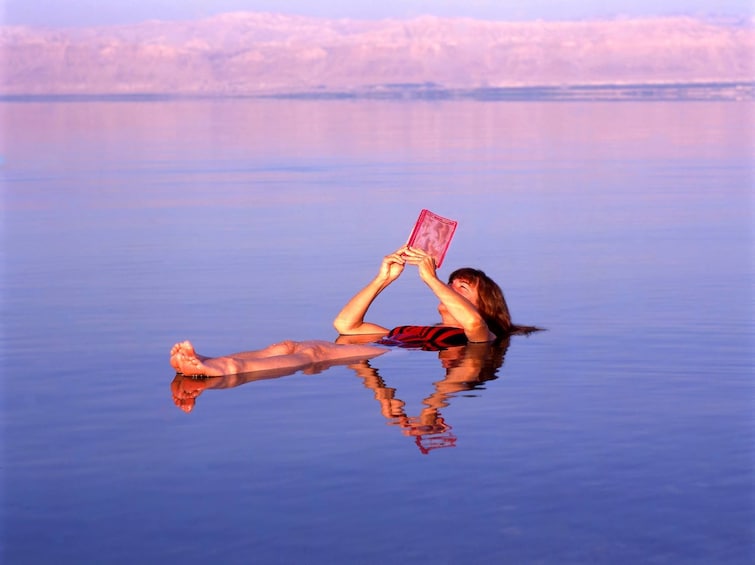 Woman reads a book while floating in the Dead Sea