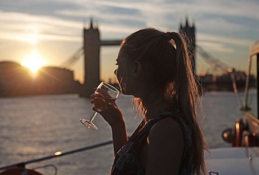 Silhouetted woman drinking wine on a evening cruise on the river Thames