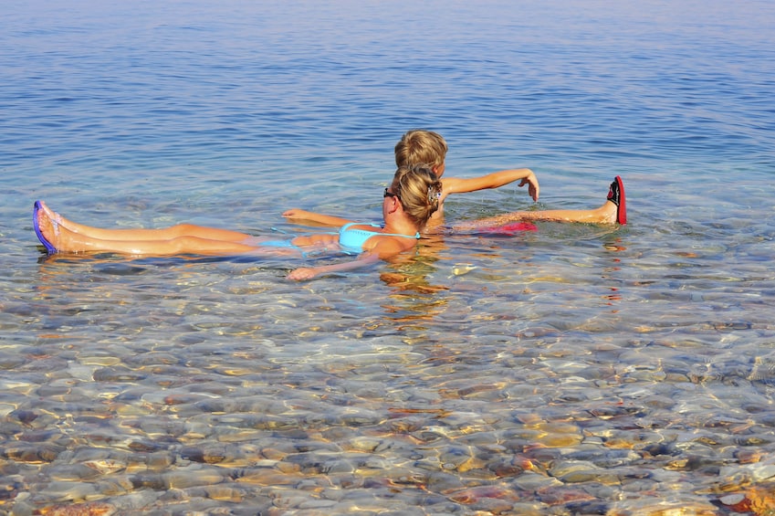 Mother and child floating in the salty water of the Dead Sea