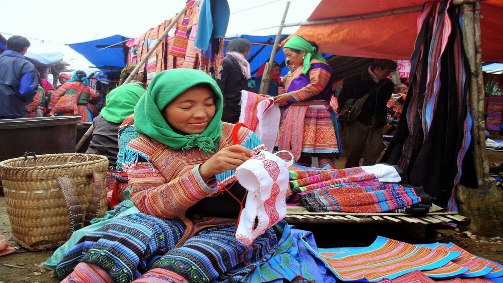 Women embroiders cloth at market in Vietnam