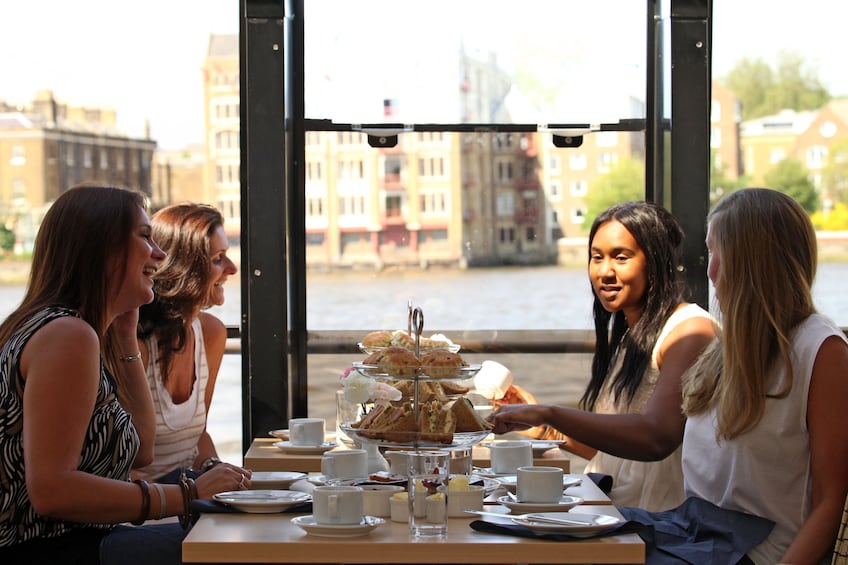 Friends have tea on an afternoon cruise on the Thames