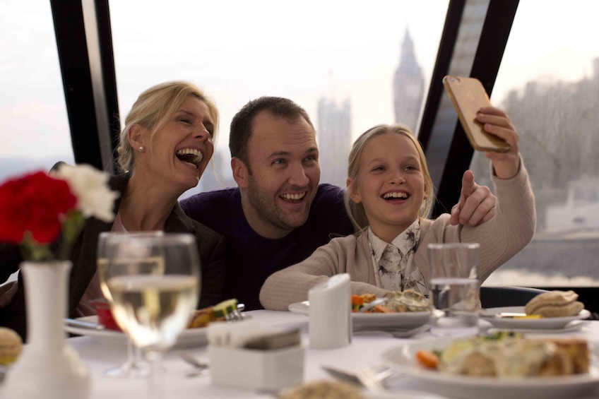 Family having lunch on a River Thames cruise with Big Ben in the background