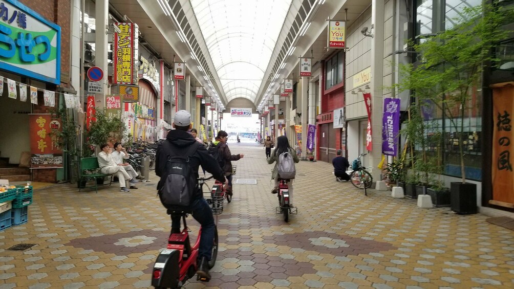 Group riding electric bikes through a street in Hiroshima