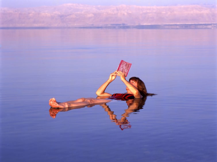 Woman floating and reading in the Dead Sea in Jerusalem