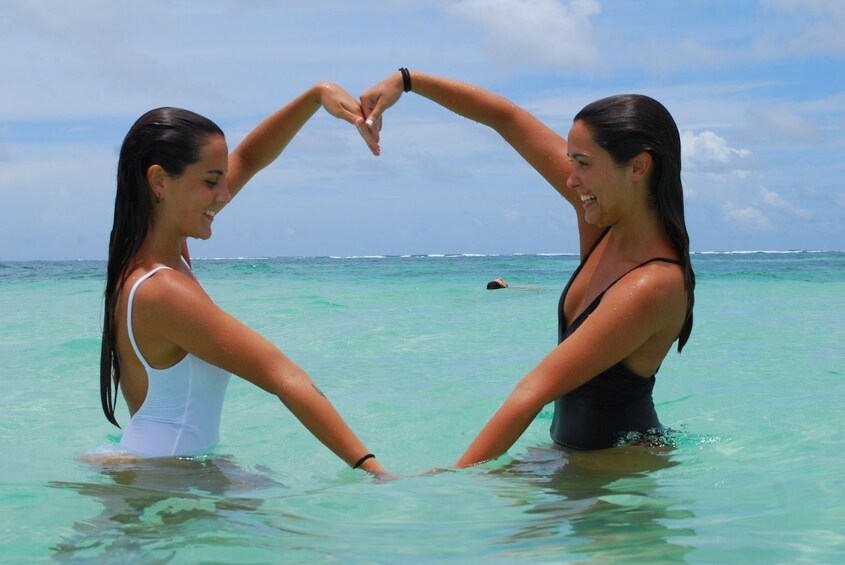 Two ladies making a heart shape with their arms at a beach in Punta Cana