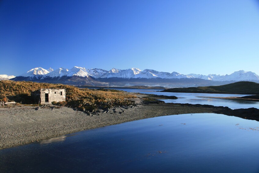 Serene waters of Beagle Channel with small house on an island and mountains in background