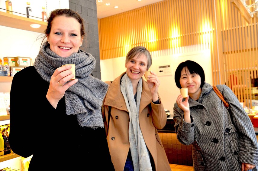 Three women holding small cups