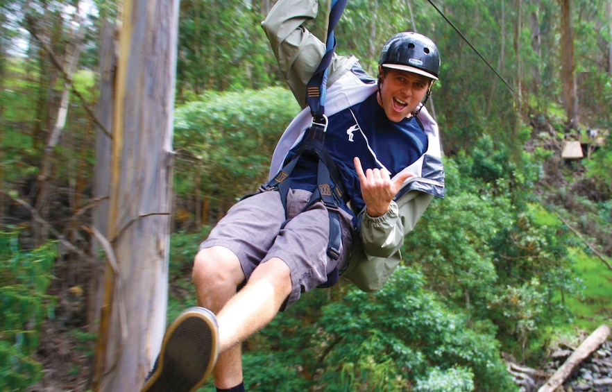 Man flashing hang loose hand sign while ziplining in Maui