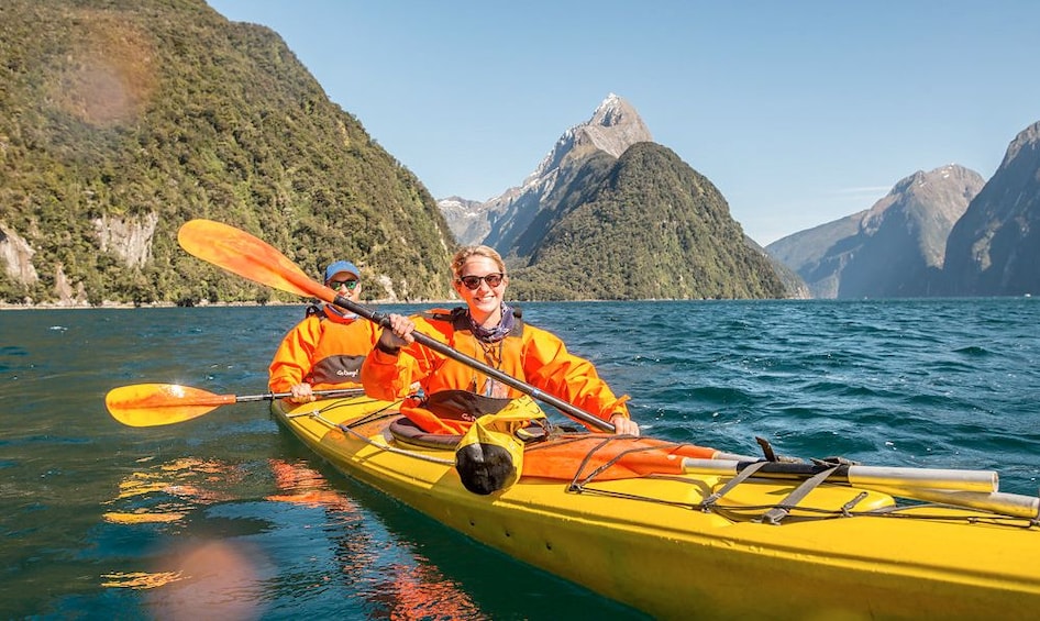 Couple on a kayaking trip on a sunny day along the Milford Sound