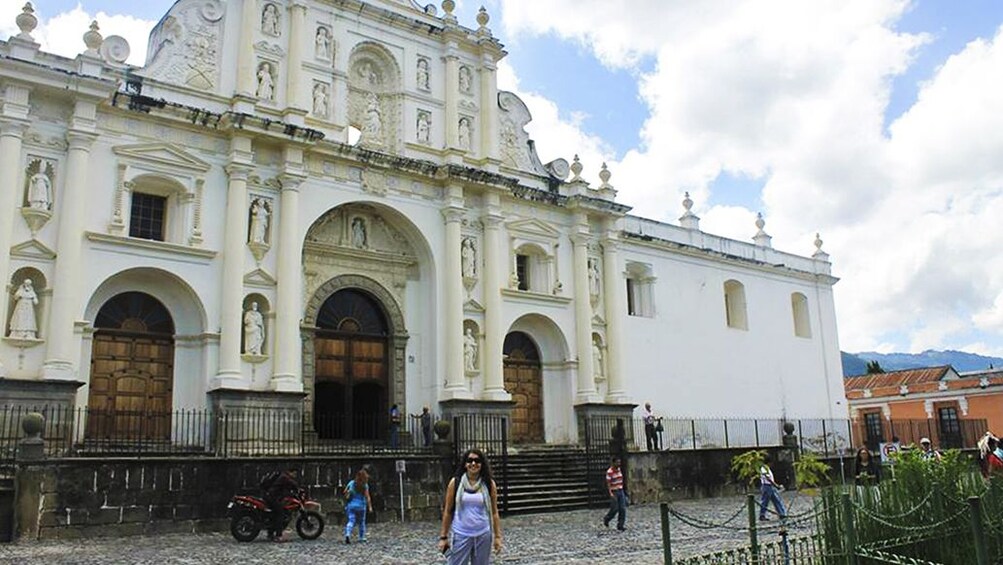 Woman poses in front of Antigua Guatemala Cathedral on a sunny day