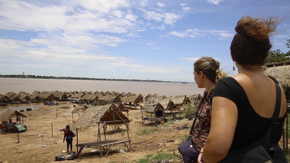 Tour group looking at grass huts on the beach in Cambodia