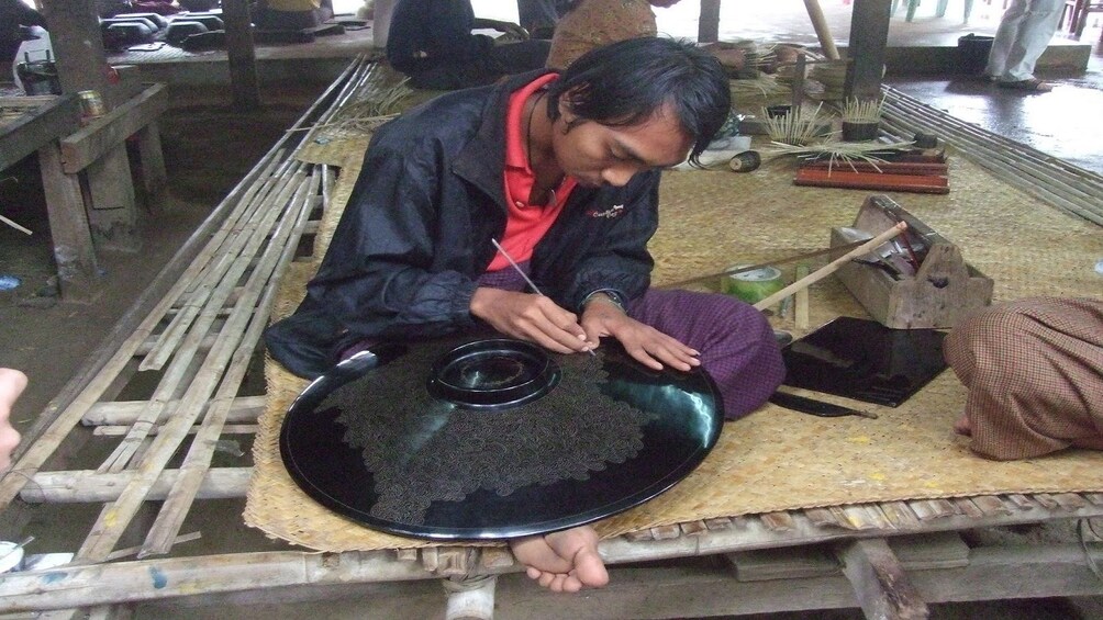 Man painting black platter with lacquer in Old Bagan, Myanmar