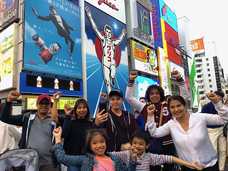 Group of people pose for a photo on a busy Osaka street