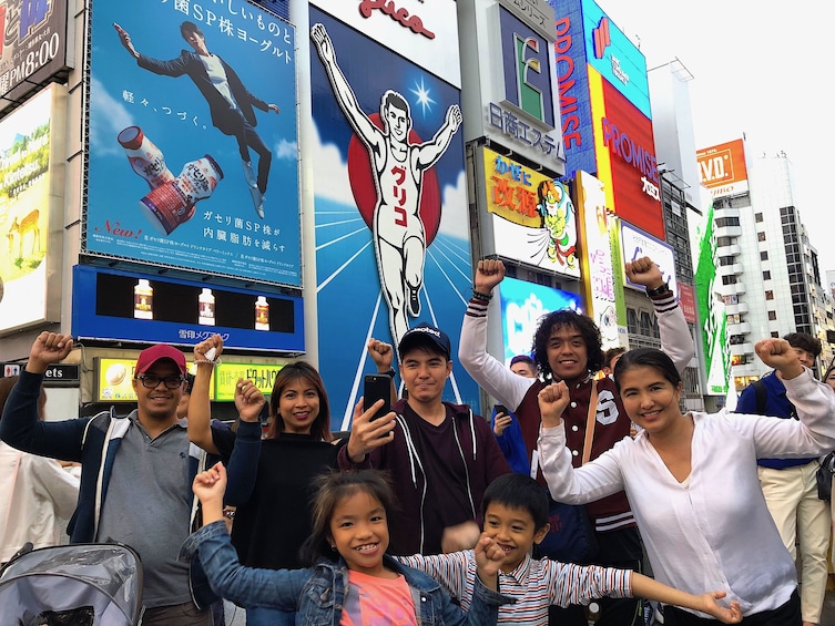 Group of people pose for a photo on a busy Osaka street