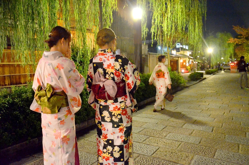 Women dressed as Geishas next to a Bamboo garden