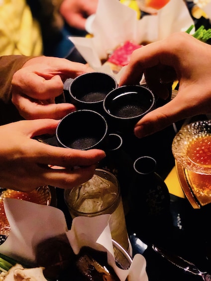 Three people cheers with cups of green tea