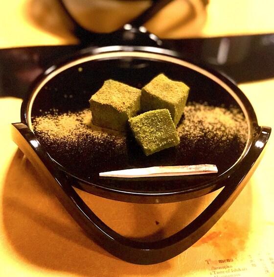 Three green cubes seasoned with salt on a black plate