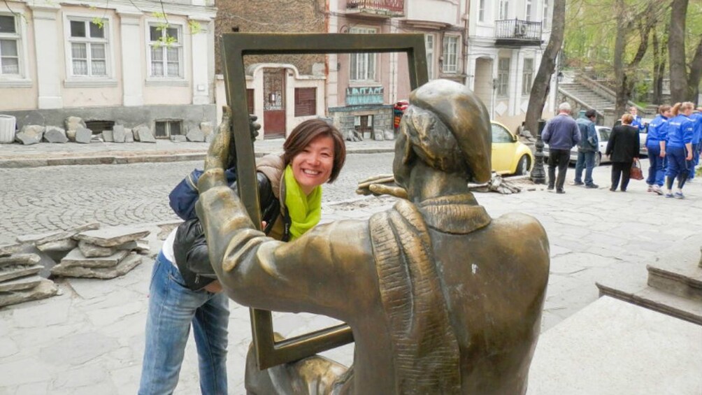 Woman taking a photo with a statue in Plovdiv