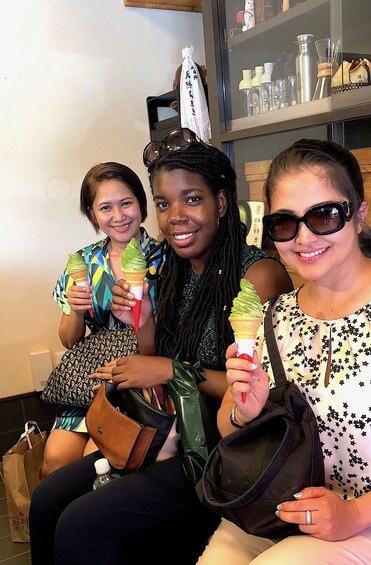 Three women hold green tea ice cream in cones