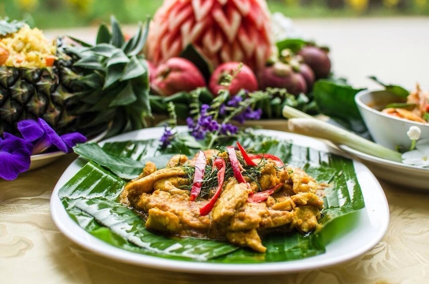 Closeup of chicken dish with fruit display in background