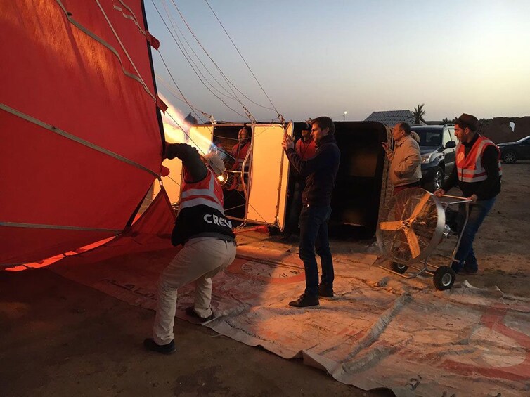 Guides hold hot air balloon sideways as they prepare to take off