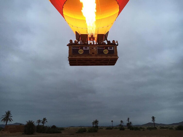 Basket of hot air balloon with large flame and balloon above
