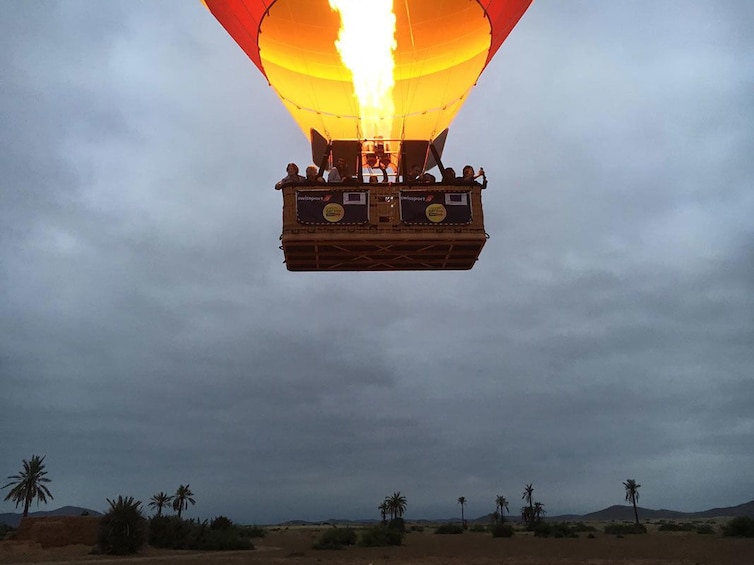 Basket of hot air balloon with large flame and balloon above