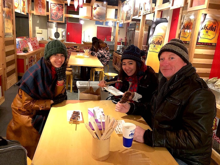 Three people at a table waiting for food at the Osaka Market