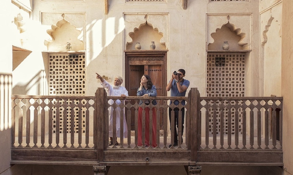 Old woman pointing out the Nizwa Fort to a couple