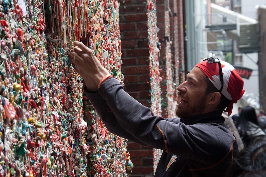 Man adding to the famous Gum Wall in Seattle