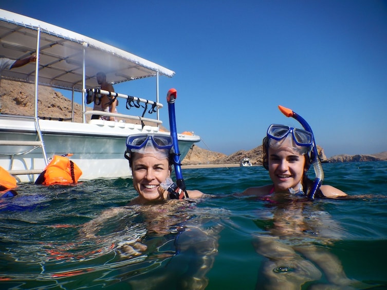 Two snorkelers in the water with masks off look at camera