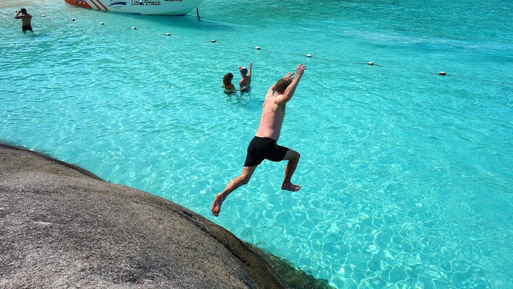 Man jumping off a rock into the water on the Similan Islands in Thailand