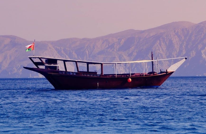 Dhow boat on a fjord with mountains in the background in Khasab 
