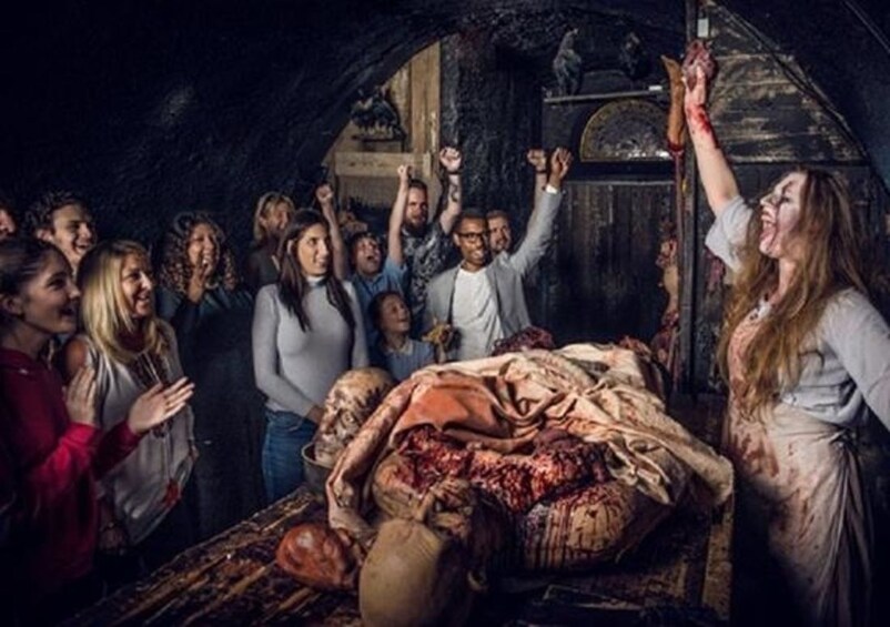 Tour group looking at a gruesome scene of a disembodied corpse and a woman with a knife