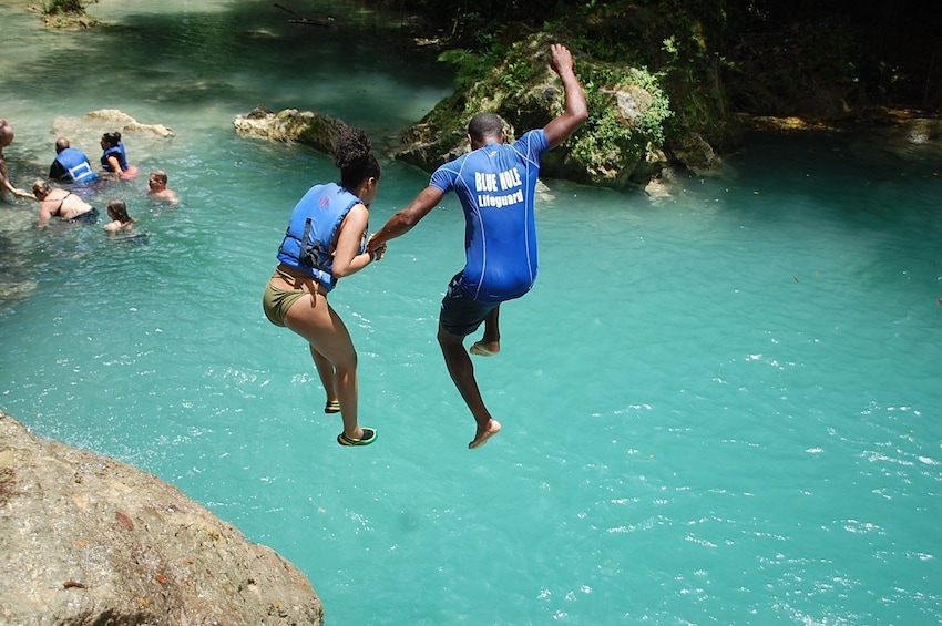 Couple jumping into the water in Jamaica