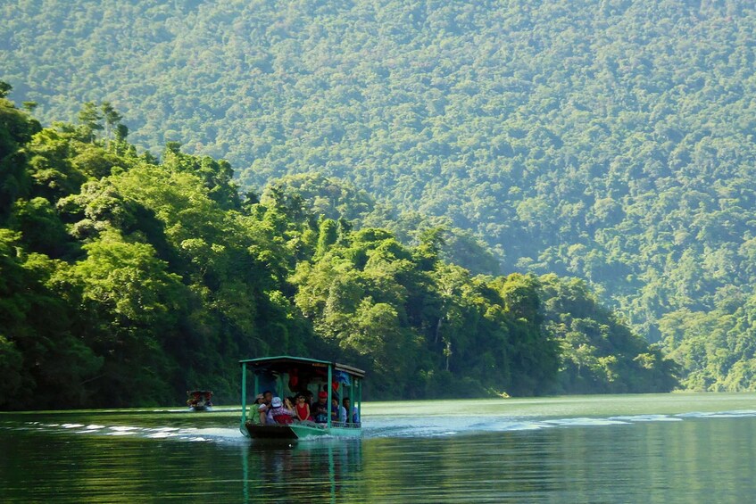 Boat on Ba Be Lake surrounded by lush landscape